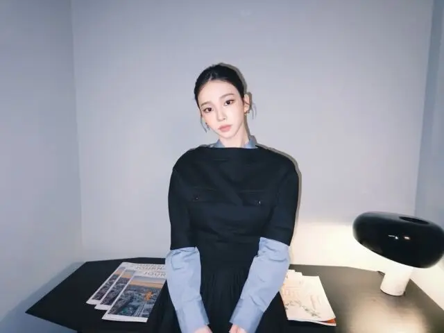 Karina提起裙摆在室内微笑展示全身造型,展现出仿佛画报般的日常生活瞬间