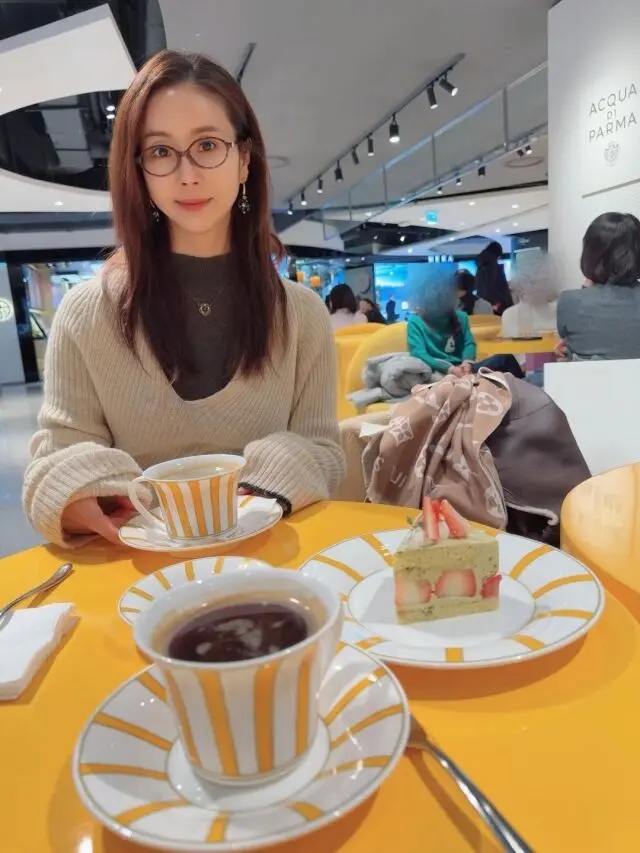 韩多感在咖啡店侧脸微笑,手持咖啡杯享受惬意午后时光