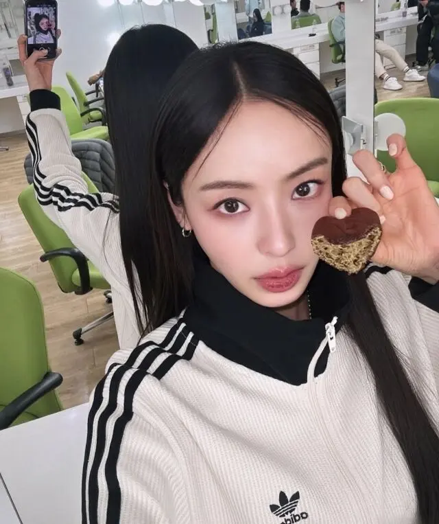 李多熙身穿灰色运动服手持爱心形状的杜拜巧克力曲奇在待机室自拍