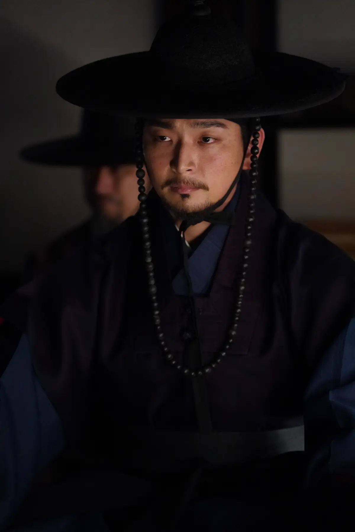 郑珍云在电影《与王同住的男人》中饰演刚正不阿的官员,剧照展示其坚毅眼神