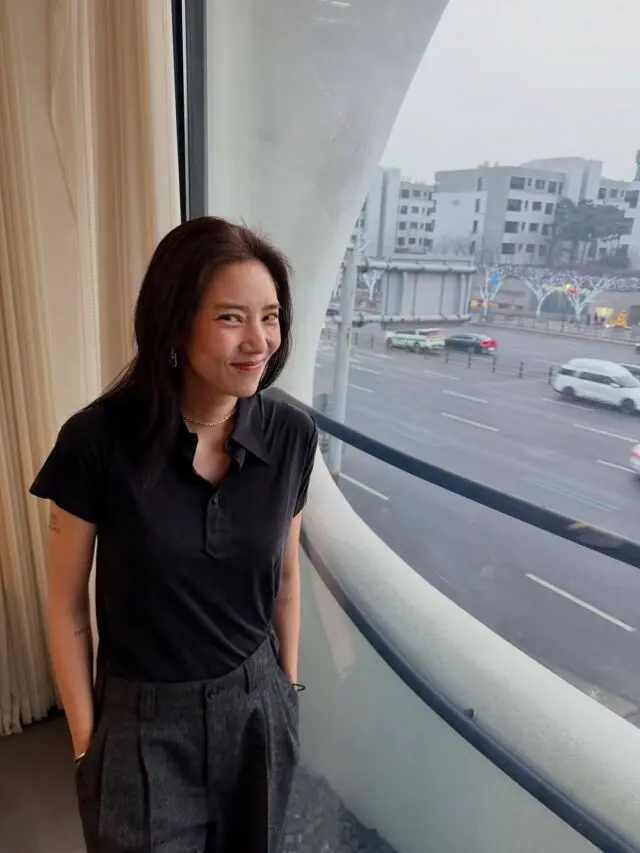 孙淡妃身穿黑色Polo衫站在窗边微笑,享受自由夫人时光