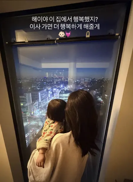 孙淡妃怀抱女儿海伊站在窗前，凝视窗外景色，作为搬家前的最后留念