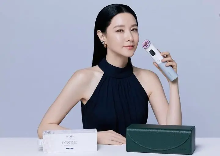 演员李英爱手持美容仪展现温婉笑容，皮肤白皙透亮。