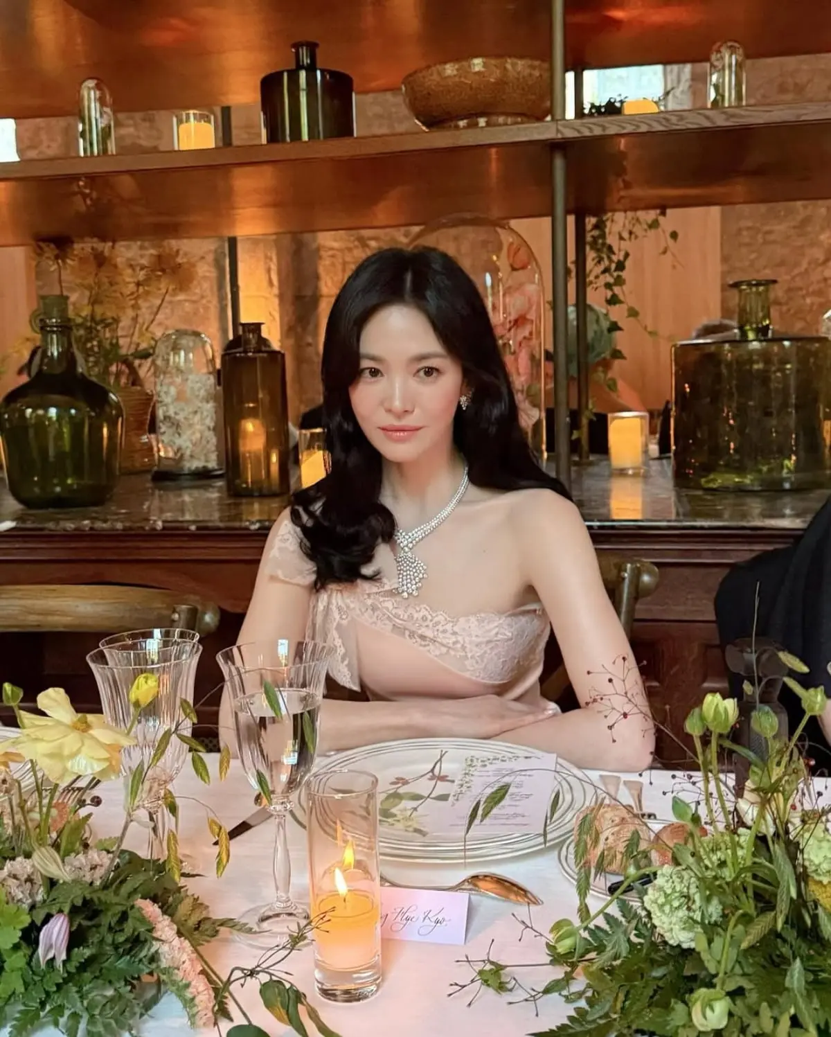 宋慧乔端坐在点缀着鲜花与烛光的高级餐桌前直视镜头